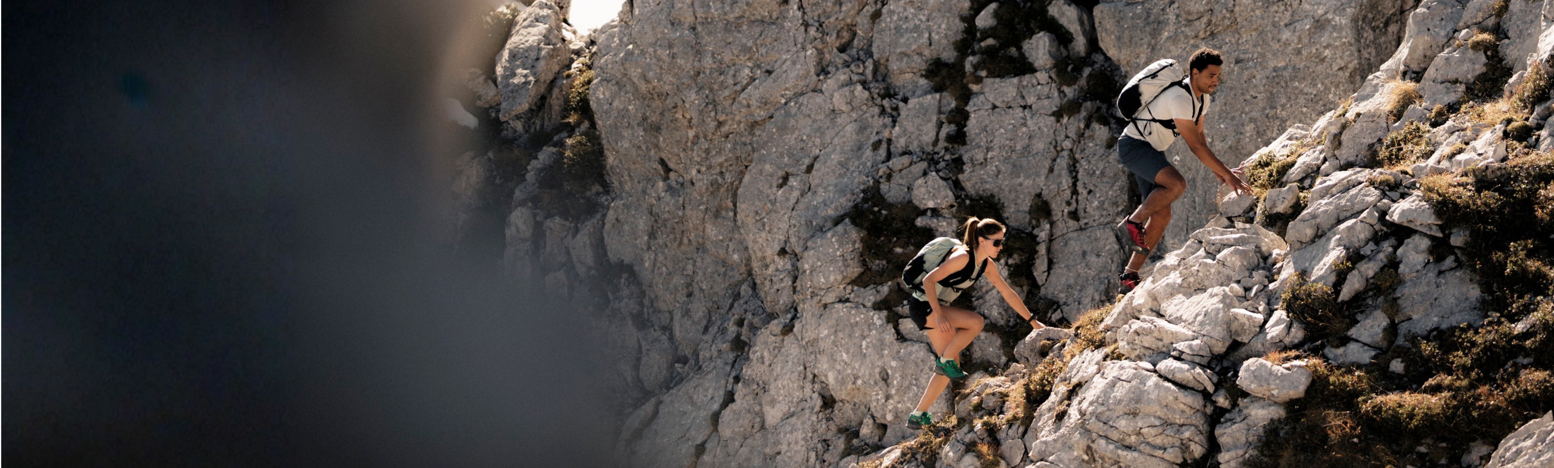 W_M_All_Mountain_S26_5000x1506 hiking, rocky terrain, outdoor activity, backpack, mountain climbing